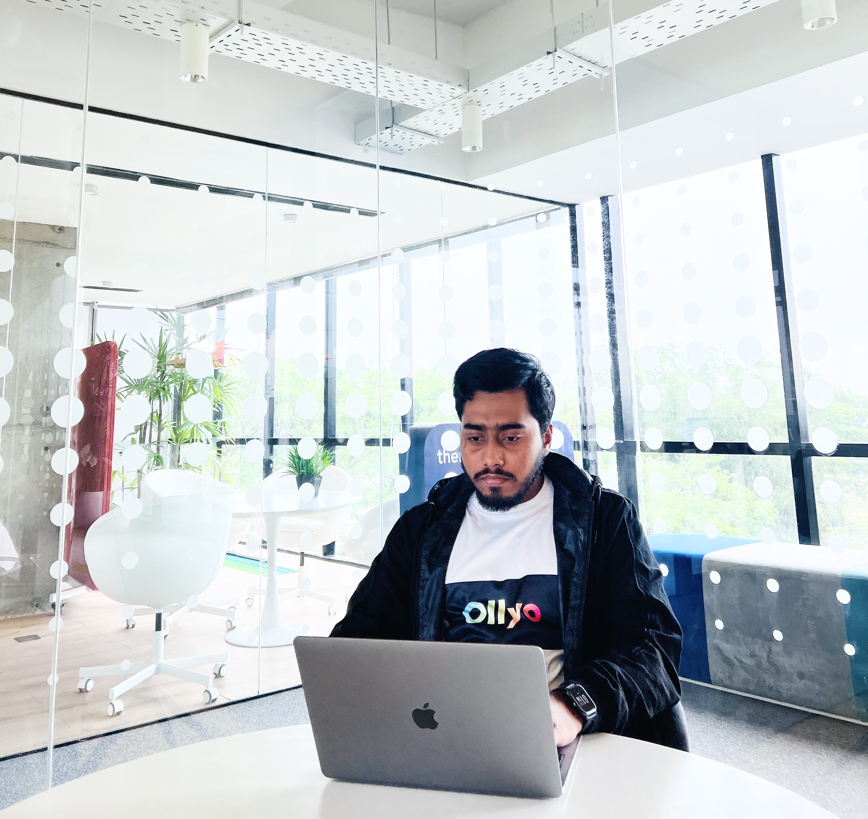 Ofi Khan working on mac and wearing an ollyo t-shirt